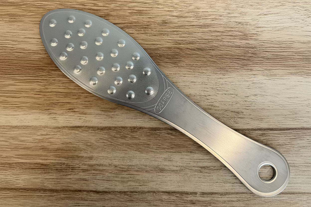 Stainless steel foot file with fine exfoliating surface designed to remove calluses and smooth rough heels”